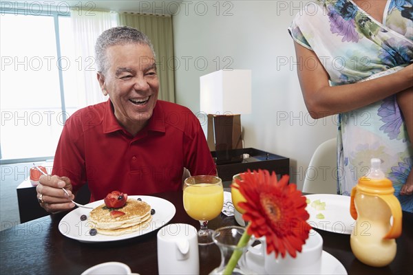 Father and daughter eating pancakes at table