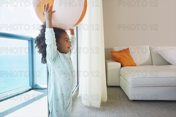 Black girl playing with beach ball in living room