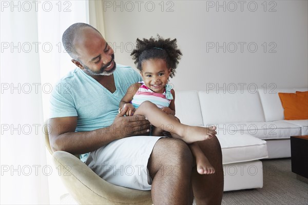 Black father and daughter sitting in living room