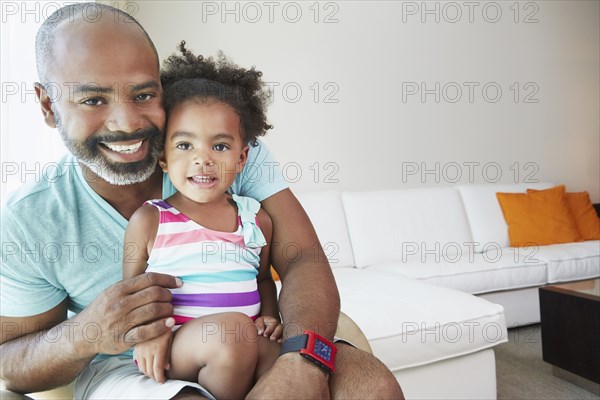 Black father and daughter sitting in living room