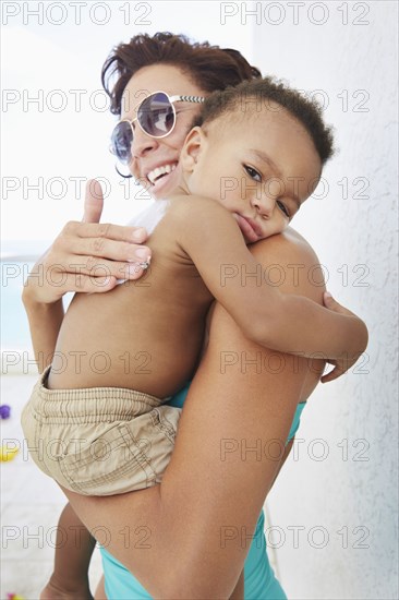 Black mother applying sunscreen to son at beach