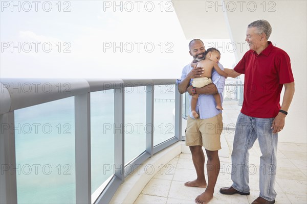 Three generations of men standing on balcony