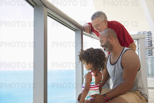 Multi-generation family overlooking ocean from balcony