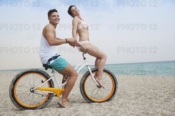 Couple riding bicycle on beach