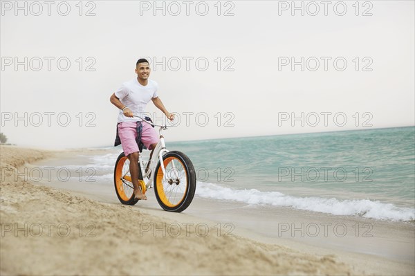 Black man riding bicycle on beach