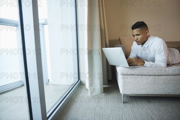 Black businessman using laptop in hotel room