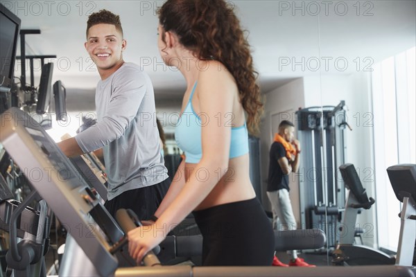 Couple using exercise machines in gym