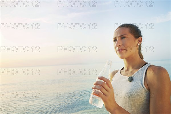 Athlete drinking water bottle on beach