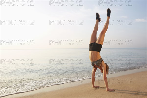 Athlete doing handstand on beach