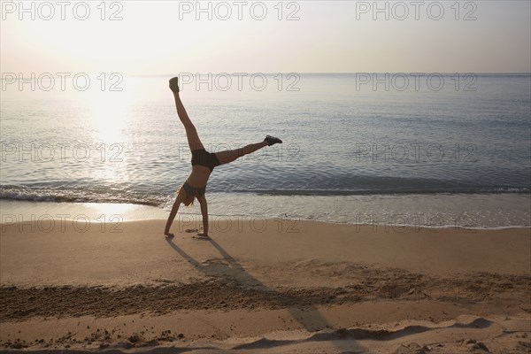 Athlete doing cartwheel on beach
