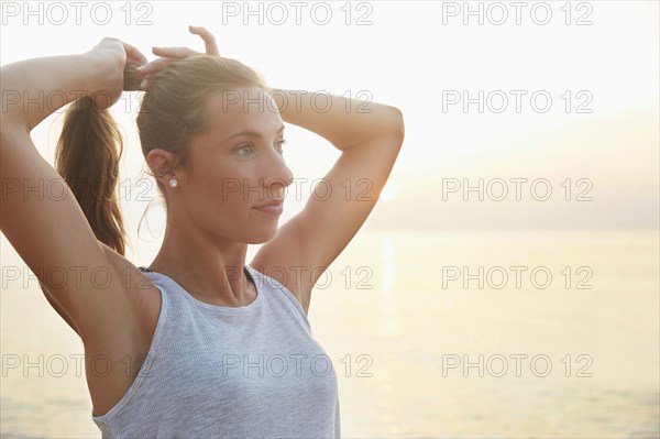 Athlete tying hair in ponytail on beach
