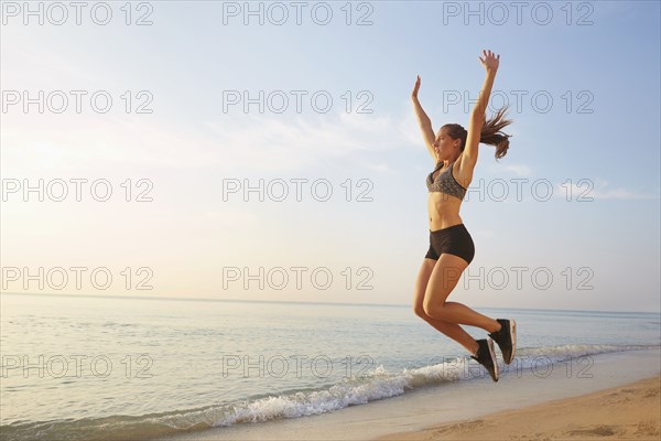 Athlete jumping for joy on beach