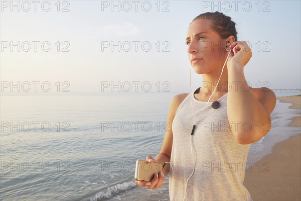 Athlete listening to earphones on beach