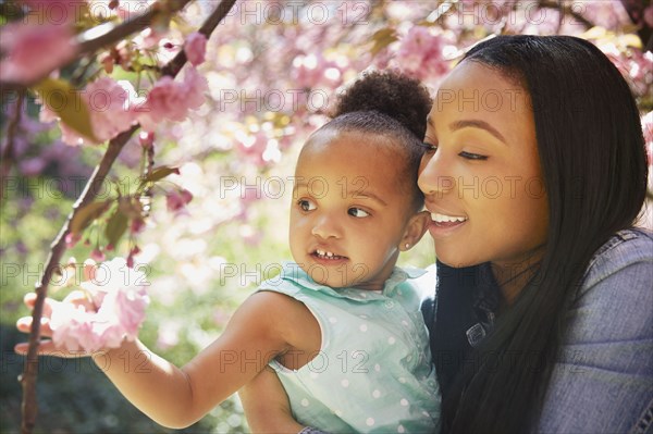 Mother and daughter admiring flowering tree in park