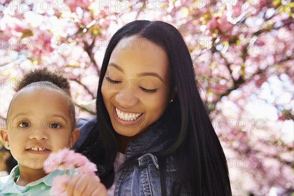 Mother and daughter under flowering tree in park