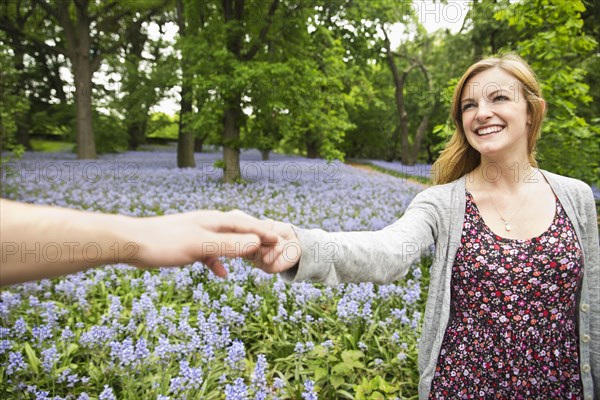 Caucasian couple holding hands in field of flowers