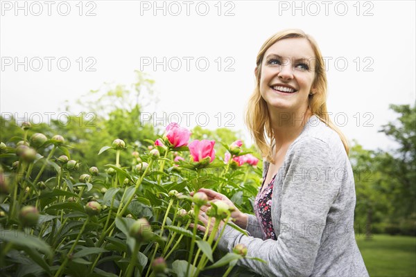 Caucasian woman smelling flowers in park