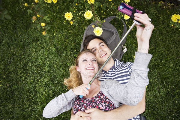 Caucasian couple taking selfie with cell phone in grass