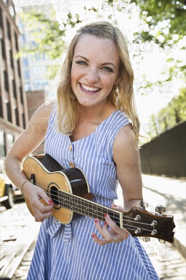 Caucasian woman playing ukulele in city