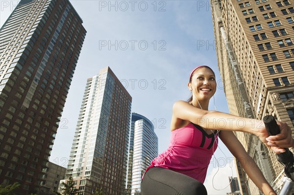 Hispanic woman riding bicycle under highrise buildings