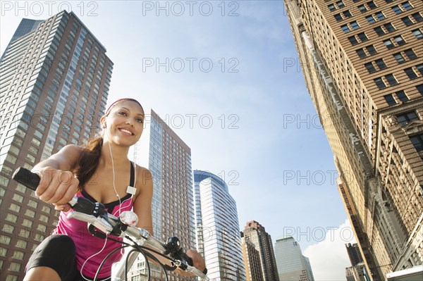 Hispanic woman riding bicycle under highrise buildings