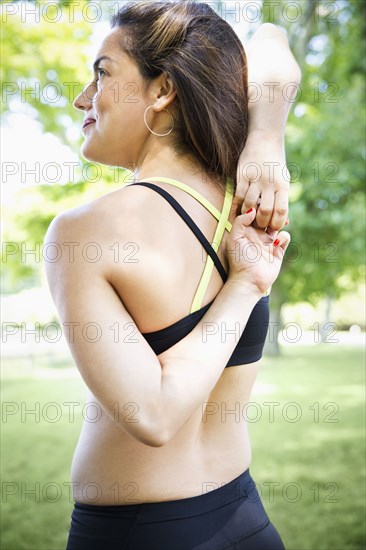 Mixed race woman stretching in grass