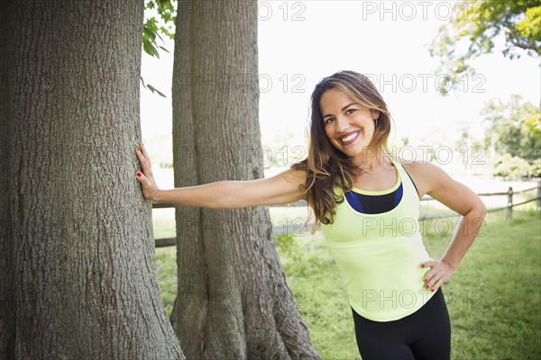 Mixed race woman leaning on tree