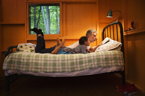 Father and daughter reading on bed