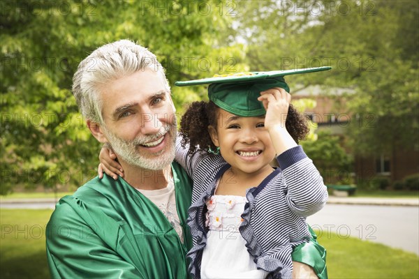 College graduate father holding daughter