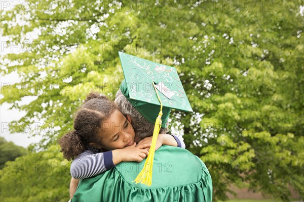 College graduate father hugging daughter