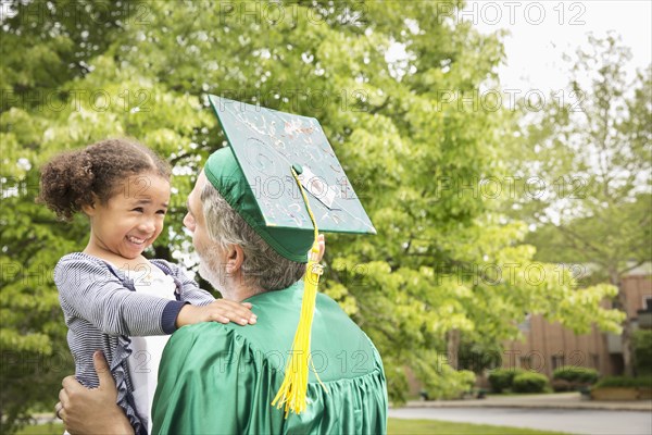 College graduate father hugging daughter