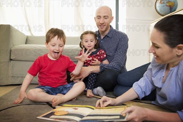 Family reading book on floor in living room