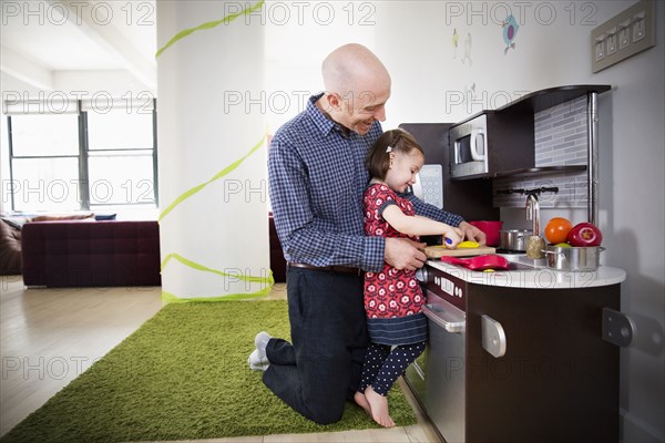 Father and daughter playing in toy kitchen