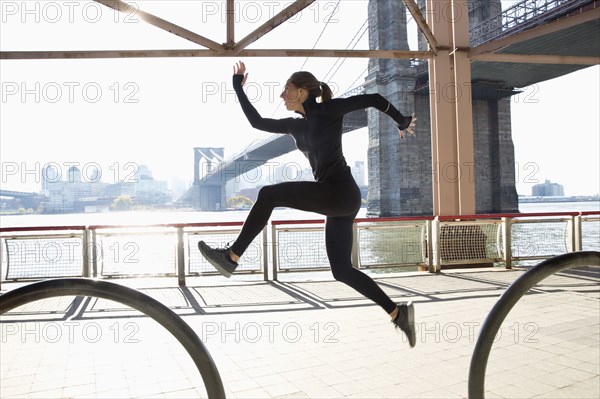 Caucasian runner jumping on waterfront