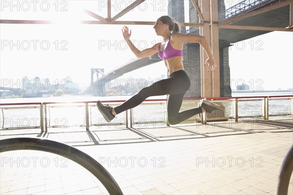 Caucasian runner jumping on waterfront