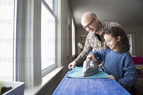 Father teaching daughter to iron fabric