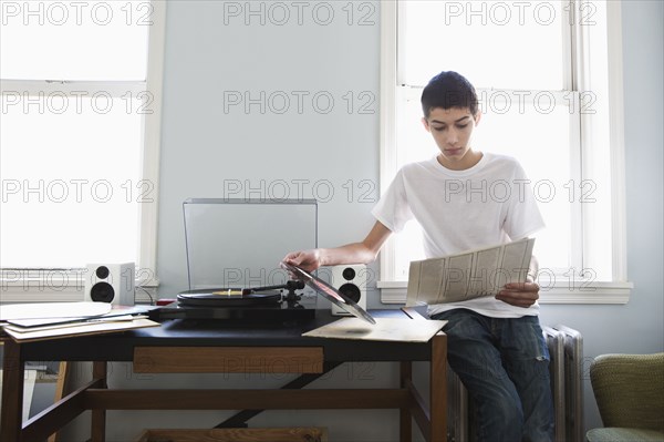 Mixed race teenage boy listening to records