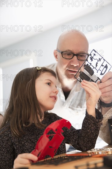 Caucasian father and daughter building model toy