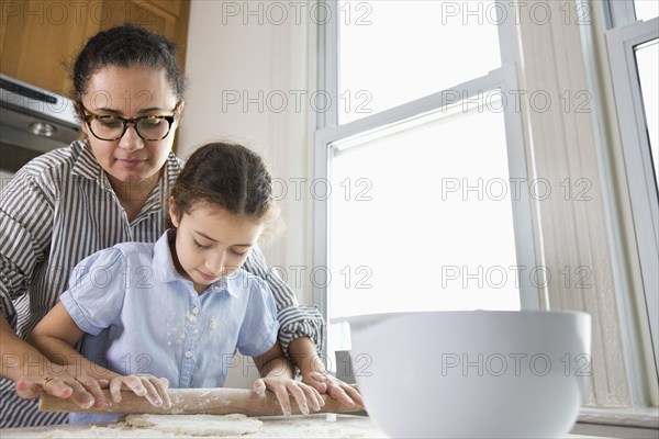 Mother teaching daughter to bake in kitchen