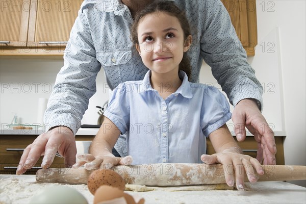 Mother teaching daughter to bake in kitchen