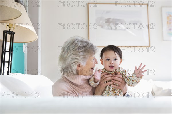 Grandmother and granddaughter hugging on sofa