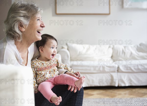 Grandmother holding granddaughter in living room