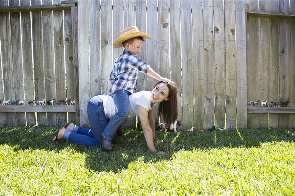 Caucasian boy wearing cowboy hat sitting horseback on mother