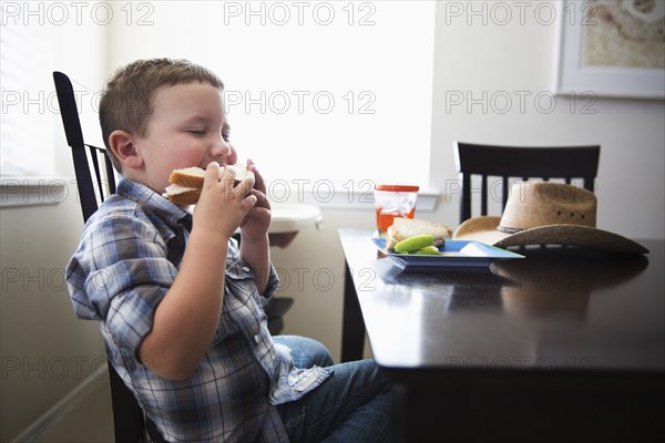 Caucasian boy eating sandwich at table