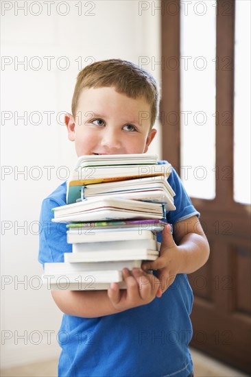 Caucasian boy carrying stack of books