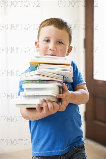 Caucasian boy carrying stack of books