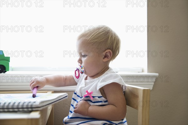Caucasian baby girl drawing with crayon