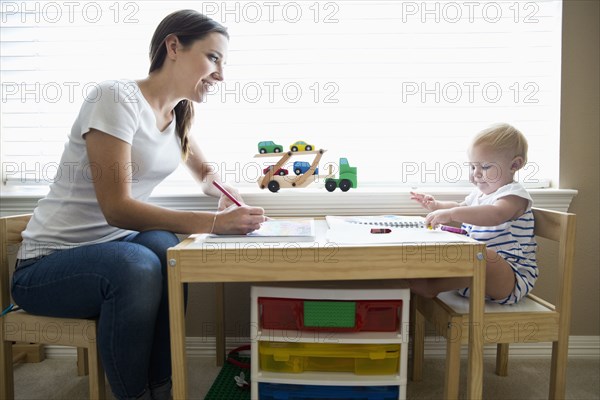 Caucasian mother and baby daughter using coloring books