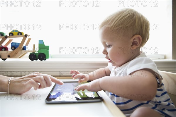 Caucasian mother helping baby girl use digital tablet