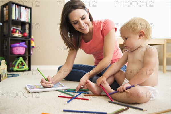 Caucasian mother and baby girl using colored pencils